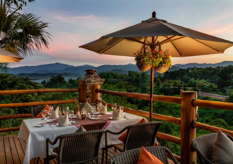 Outdoor patio and balcony, with white dining tables and a beige umbrellas