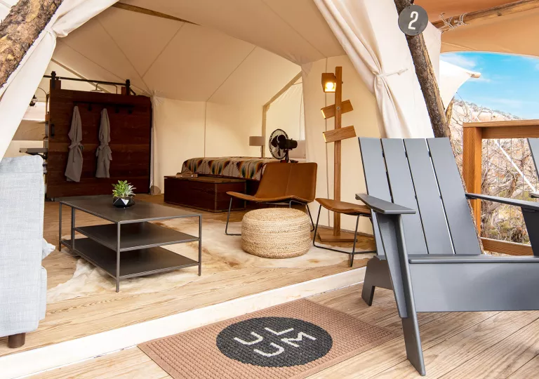 Outdoor luxury tent with furniture and two robes hanging up