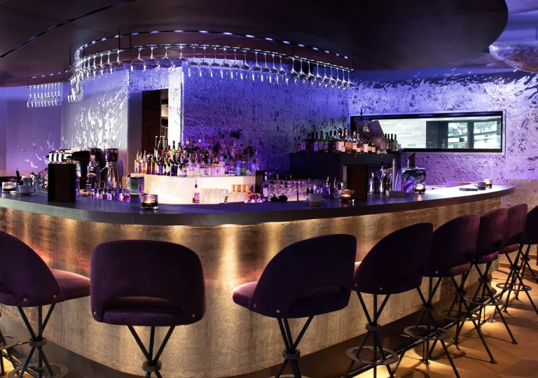 Bar and lounge with tall stools and purple lights along the walls