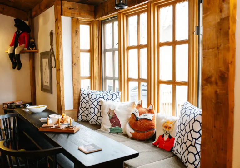 A cozy nook with wood-framed windows and an assortment of pillows at the Rabbit Hill Inn in Vermont.
