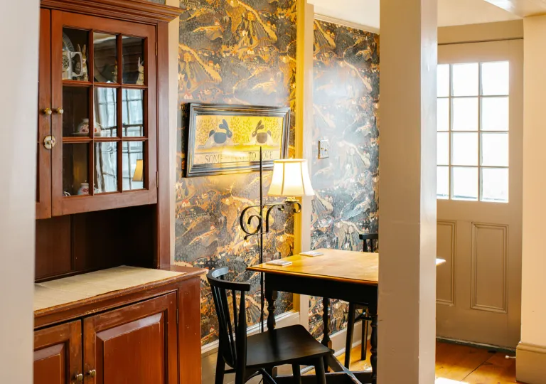 A room featuring traditional dark wood furniture and landscape-themed wallpaper at Rabbit Hill Inn in Lower Waterford, Vermont.