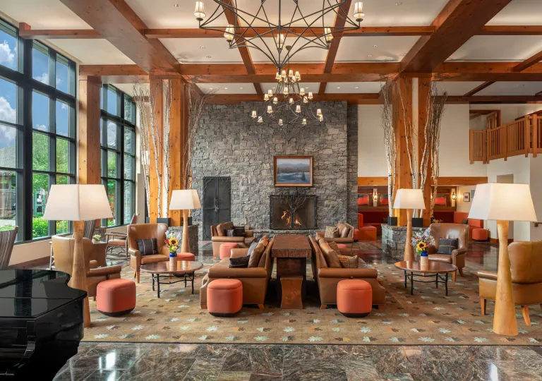 The rustic and grand lobby of The Lodge at Spruce Peak in Stowe, Vermont, featuring soaring timber-frame ceilings and a massive stone fireplace.