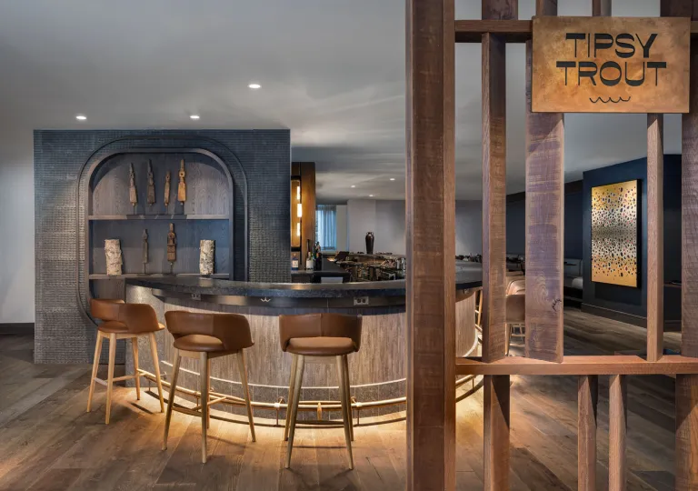 The bar at The Lodge at Spruce Peak in Stowe, Vermont, with natural wood elements and modern bar stools.