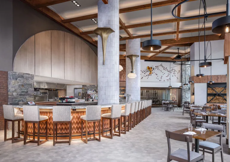 The restaurant at Spruce Peak in Stowe, Vermont, that features high ceilings with wooden beams and extensive bar seating.