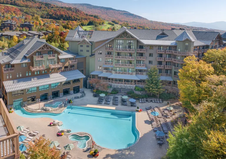 The Lodge at Spruce Peak in Stowe, Vermont, featuring its large outdoor swimming pool and mountain views.