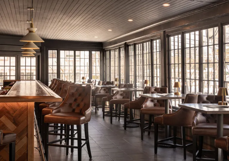 The interior of the bar at The Wentworth Inn in Jackson, New Hampshire, which features a modern-day tavern ambiance with dark wood and leather seating