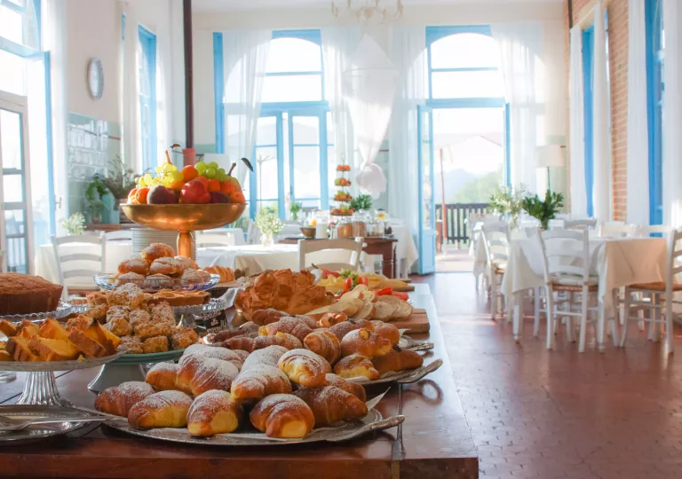 Restaurant with a large table in the center full of pastries and fruit