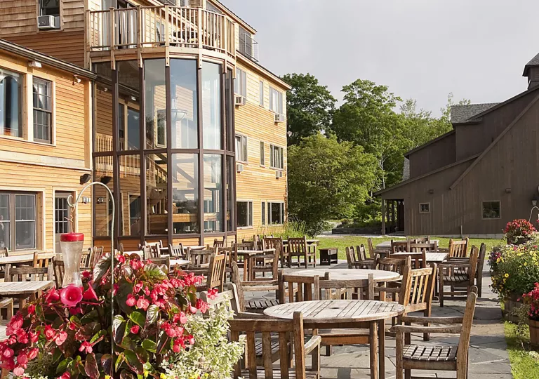 Exterior view of yellow hotel building with dining tables in front