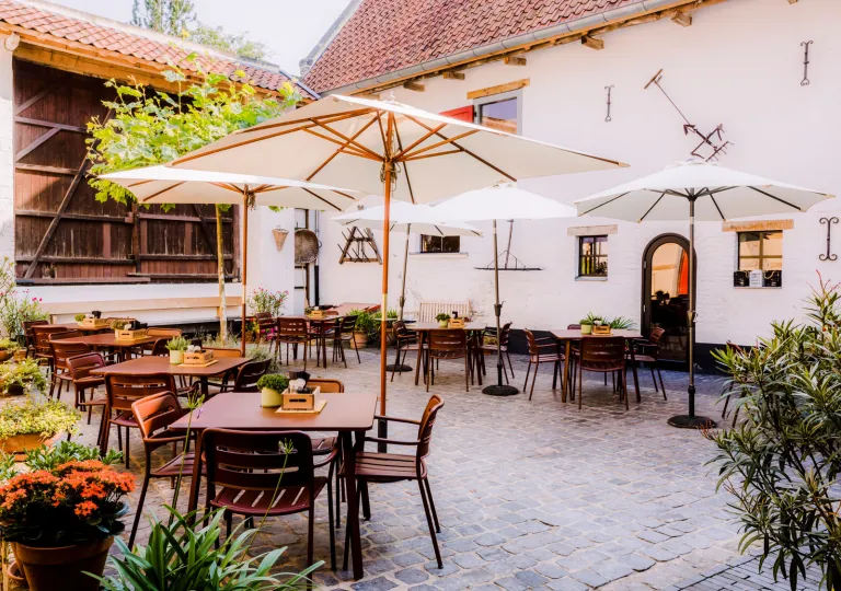 Outdoor patio with wooden chairs and tables, and large white umbrellas
