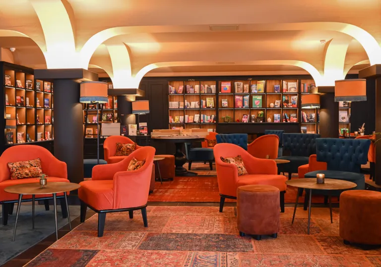 Indoor lounge area with orange, cushioned chairs and circular tables