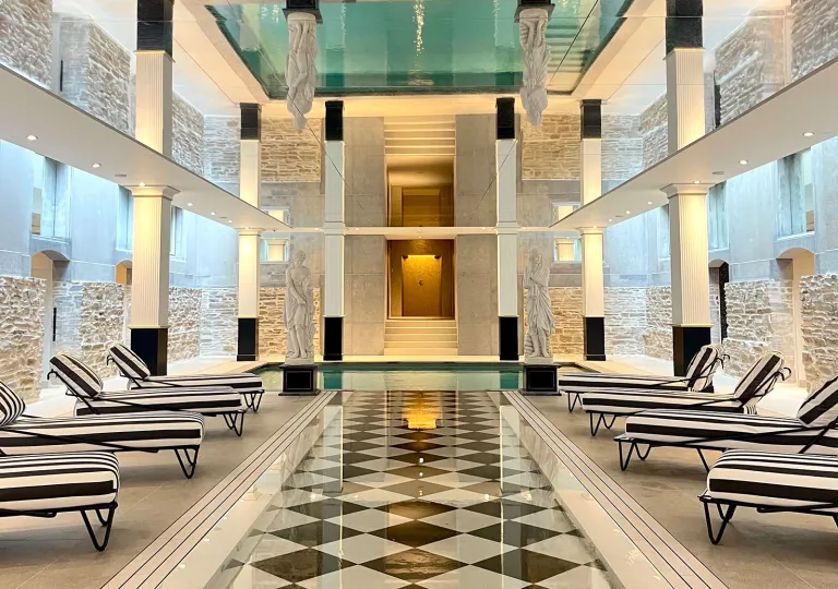 Spa room with checkered, tile floorings, striped reclining chairs and a hot tub in front