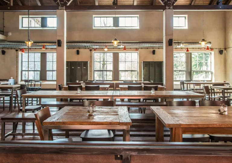 Rustic wood tables and chairs along with high ceilings and metal beams inside the restaurant at Boutique Hotel Latrán in Český Krumlov, Czech Republic.