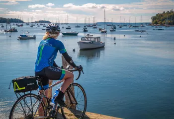 Guest with bike on pier, overlooking bay full of sailboats.