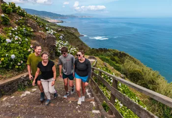 Group of people walking up stairs, with large cliffs and the ocean in the background