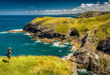 Woman standing on a grassy cliff looking out to the ocean