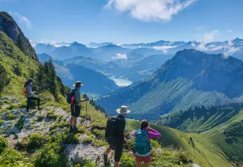 Group of people on top of a cliff looking down at grassy hills