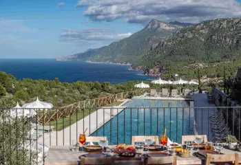 Outdoor balcony with a view of an outdoor pool and ocean in the background