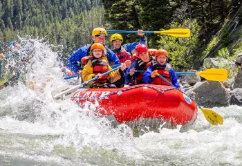 Group of adults and kids on a red raft in the middle of a river