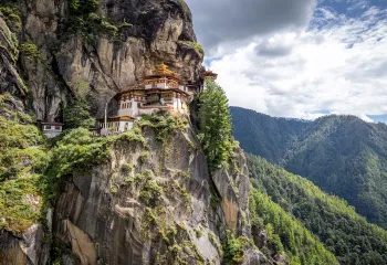 Large white temple on top of a cliff, with a valley in the distance