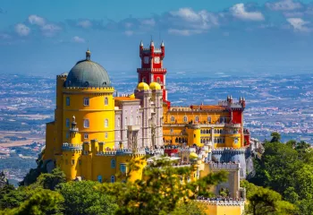 Yellow and red Spanish-style castle building with people standing on the outdoor patio