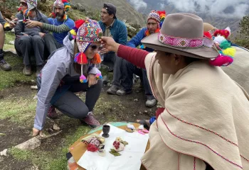 Peruvian woman blessing another woman with a plant