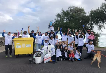 Group of people wearing white shirts, smiling with their arms up