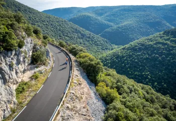 Group of people riding bikes on a road on a hill, grassy hills in the distance