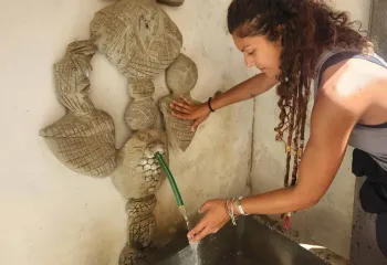Woman touching water from a stone water fountain