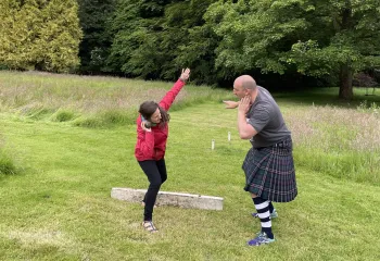 Man and woman posing to throw a steel ball in a large field