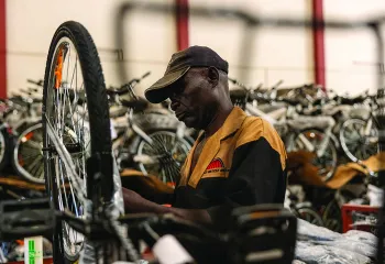 Man fixing a bike in a warehouse full of bicycles