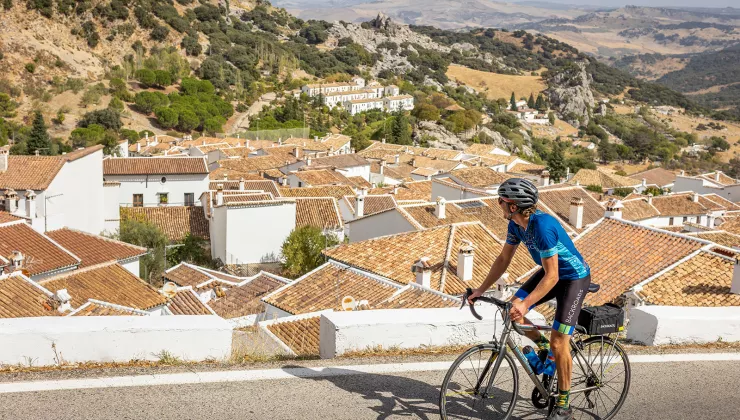 Biker riding past red tile rooftops.
