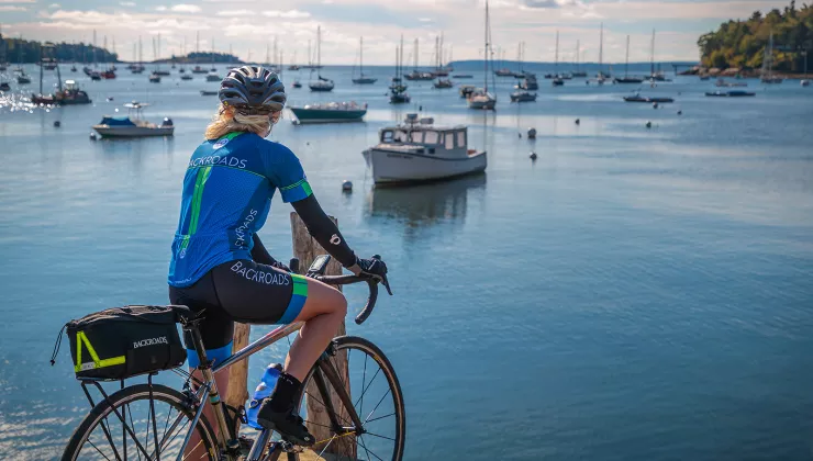 Guest with bike on pier, overlooking bay full of sailboats.