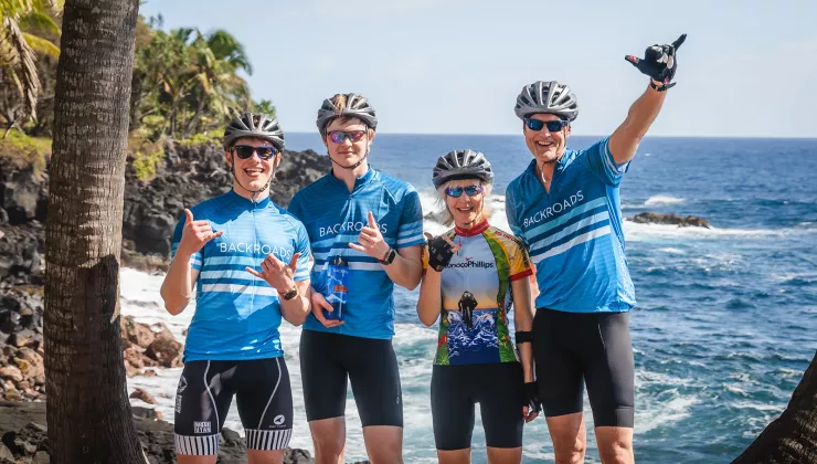 Guests posing under a palm tree by the coast in Hawaii