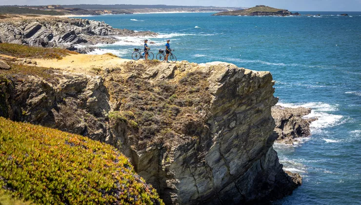 Two bikers resting on a cliff overlooking the sea