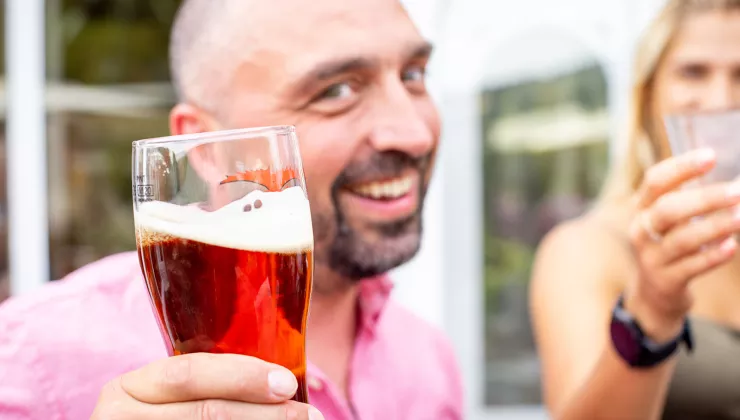 Backroads guest holding pint of dark beer.