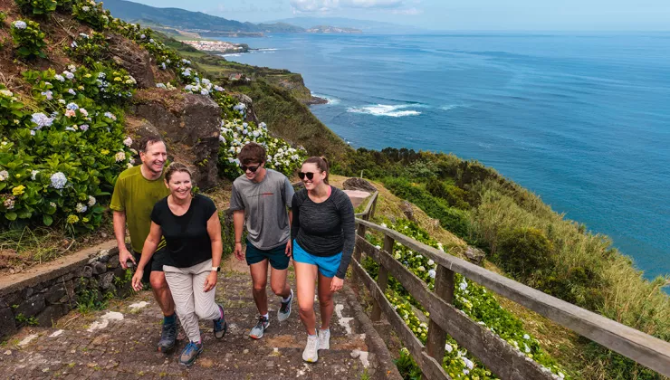 Group of people walking up stairs, with large cliffs and the ocean in the background