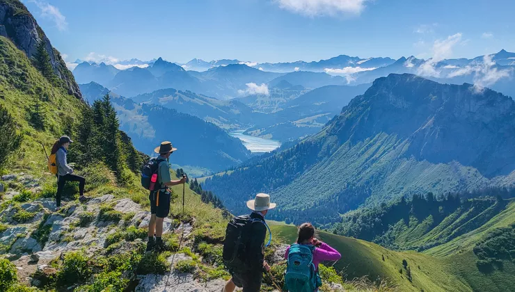 Group of people on top of a cliff looking down at grassy hills