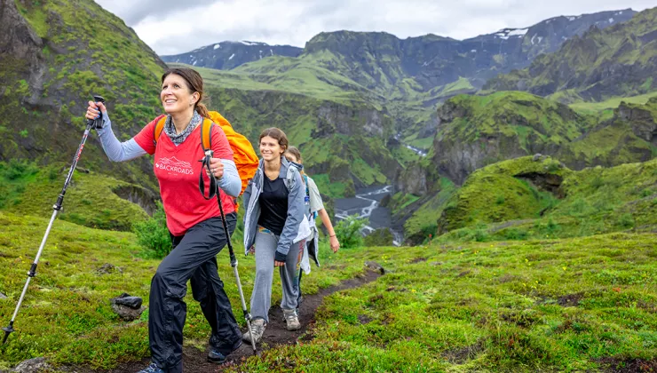 Group of women hiking up a dirt trail, with grassy mountains in the distance