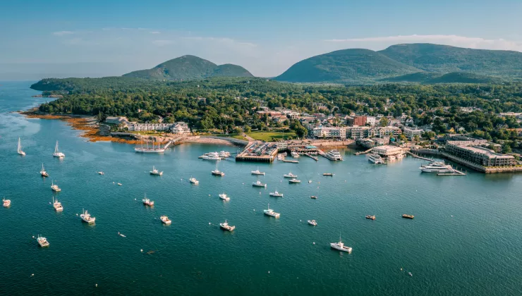 Boats scattered throughout the ocean next to a seaside town