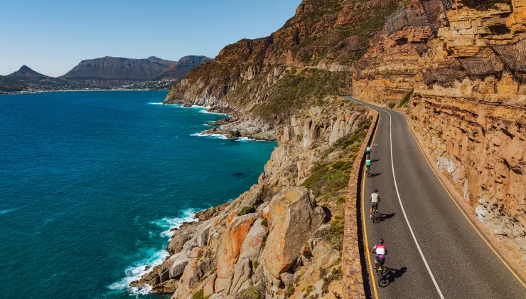 people riding bicycles down a beachfront road