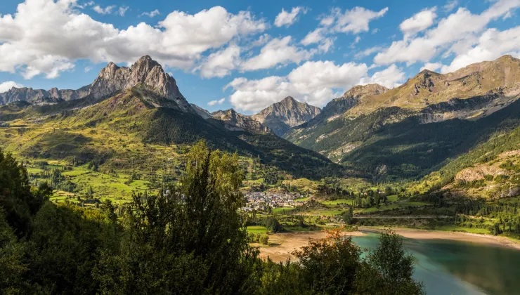 green mountains and lakes below a blue sky with white fluffy clouds