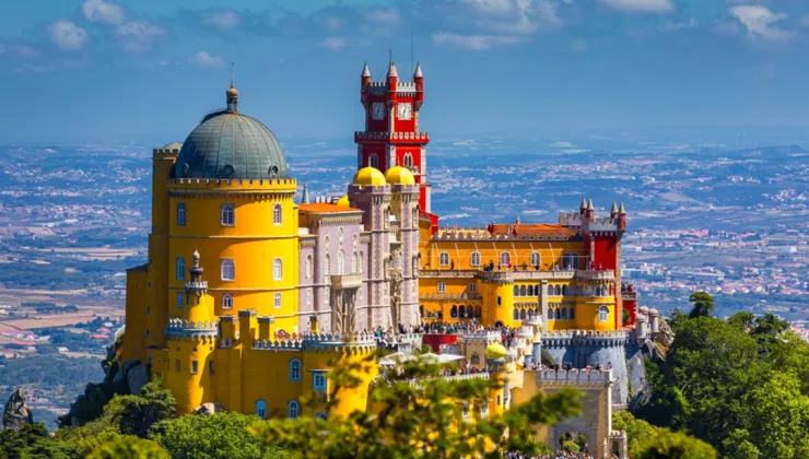Yellow and red Spanish-style castle building with people standing on the outdoor patio