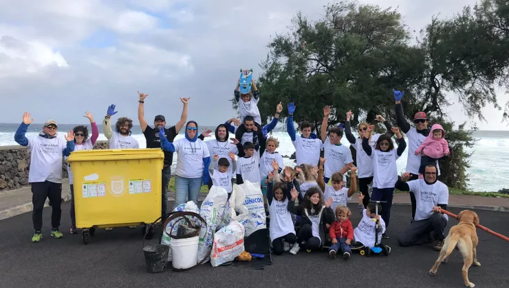 Group of people wearing white shirts, smiling with their arms up