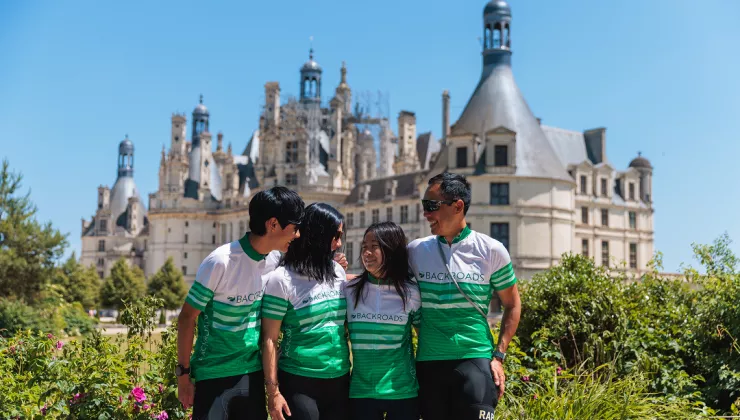 Family in white and green biking jerseys standing in front of a rustic, church-like building