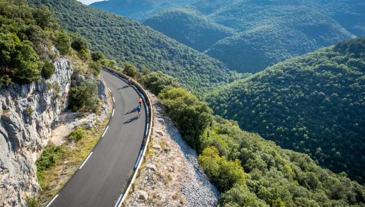 Group of people riding bikes on a road on a hill, grassy hills in the distance