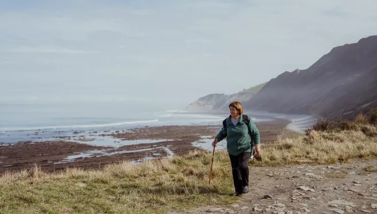 Woman walking through a dirt trail by the ocean