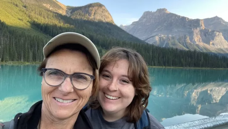 Mom and daughter smiling in front of a large lake