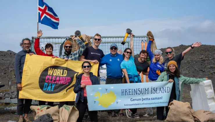 Group of people smiling while holding up large banners and an Iceland flag