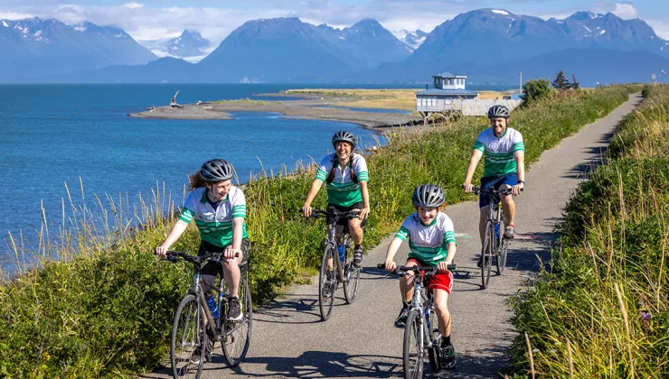 Family biking on a road along a large ocean to the left