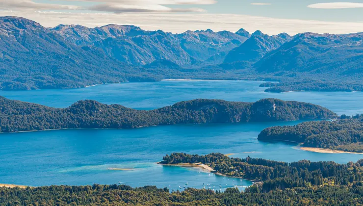 Sky view of a large lake, surrounded by tall mountains and trees